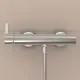 Brausearmatur von Ideal Standard in silberner Ausführung, wandmontiert, mit einem Rohrkörper und einem Handbrauseschlauch, an einer hellen Wand installiert.